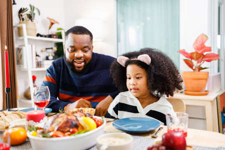 African American family. Merry Christmas. Happy family are having dinner at home. Celebration holiday and togetherness near Christmas tree.の写真素材