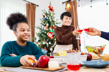 African American family. Merry Christmas. Happy family are having dinner at home. Celebration holiday and togetherness near Christmas tree.の写真素材