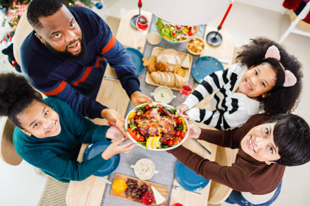 African American family. Merry Christmas. Happy family are having dinner at home. Celebration holiday and togetherness near Christmas tree.の写真素材