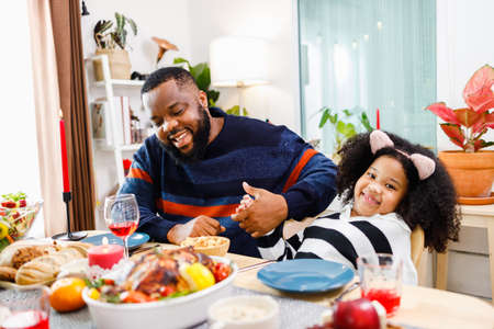 African American family. Merry Christmas. Happy family are having dinner at home. Celebration holiday and togetherness near Christmas tree.の写真素材