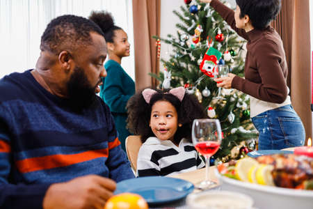 African American family. Merry Christmas. Happy family are having dinner at home. Celebration holiday and togetherness near Christmas tree.の写真素材