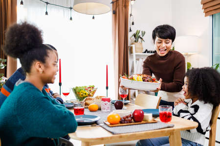 African American family. Merry Christmas. Happy family are having dinner at home. Celebration holiday and togetherness near Christmas tree.の写真素材