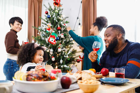 African American family. Merry Christmas. Happy family are having dinner at home. Celebration holiday and togetherness near Christmas tree.の写真素材