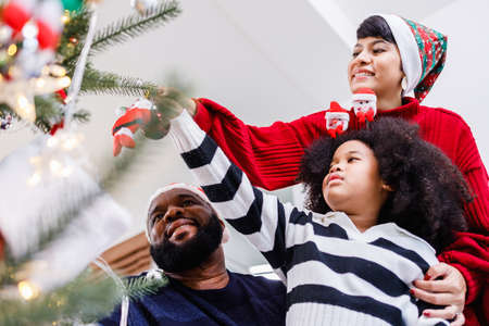 African American family help decorate the Christmas tree at home. Merry Christmas.の写真素材