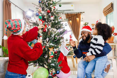 African American family help decorate the Christmas tree at home. Merry Christmas.の写真素材