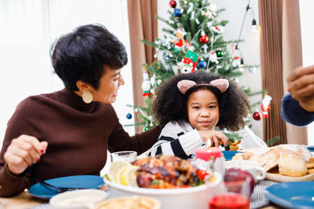 Happy family are having dinner at home. Celebration holiday and togetherness near Christmas tree. African American family. Merry Christmas.の写真素材