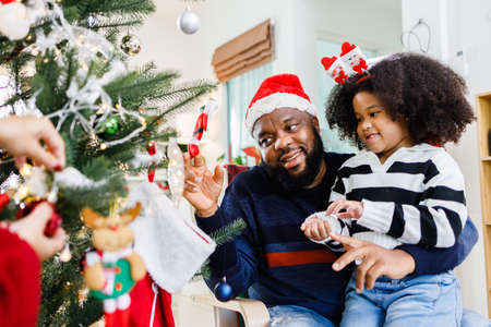 African American family help decorate the Christmas tree at home. Merry Christmas.の写真素材