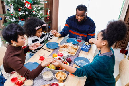 Families together to pray before meals at home. Celebration holiday togetherness near Christmas tree. African American family. Merry Christmas.の写真素材