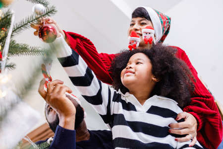 African American family help decorate the Christmas tree at home. Merry Christmas.の写真素材