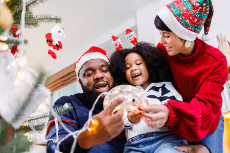 African American family help decorate the Christmas tree at home. Merry Christmas.の写真素材