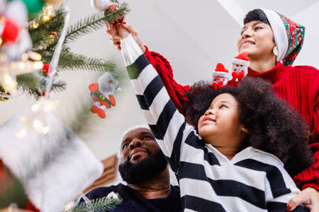 African American family help decorate the Christmas tree at home. Merry Christmas.の写真素材