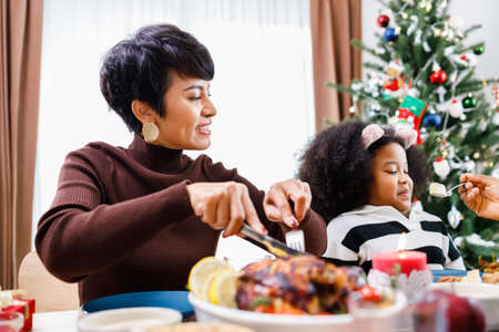 Happy family are having dinner at home. Celebration holiday and togetherness near Christmas tree. African American family. Merry Christmas.の写真素材