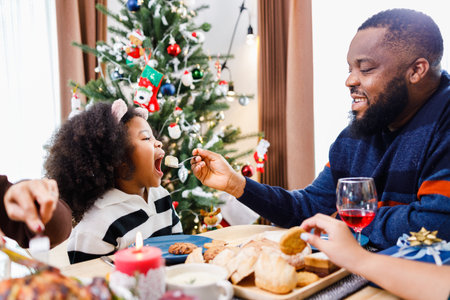 Happy family are having dinner at home. Celebration holiday and togetherness near Christmas tree. African American family. Merry Christmas.の写真素材