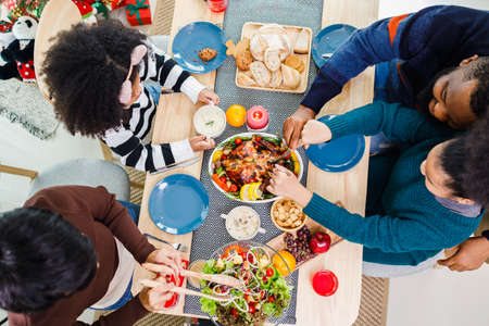 Happy family are having dinner at home. Celebration holiday and togetherness near Christmas tree. African American family. Merry Christmas.の写真素材