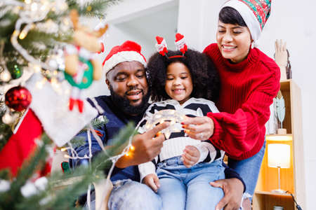 African American family help decorate the Christmas tree at home. Merry Christmas.の写真素材
