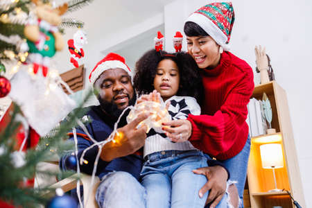 African American family help decorate the Christmas tree at home. Merry Christmas.の写真素材