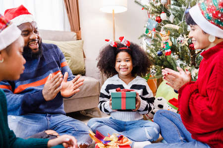 African American family surprising with a gift on Christmas day. Merry Christmas. Happy family.の写真素材