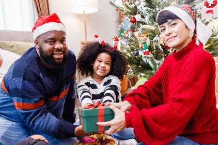 African American family surprising with a gift on Christmas day. Merry Christmas. Happy family.の写真素材
