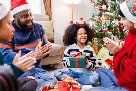 African American family surprising with a gift on Christmas day. Merry Christmas. Happy family.の写真素材
