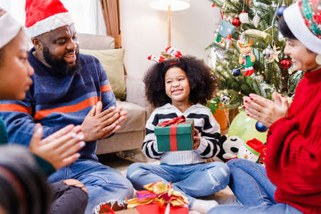 African American family surprising with a gift on Christmas day. Merry Christmas. Happy family.の写真素材