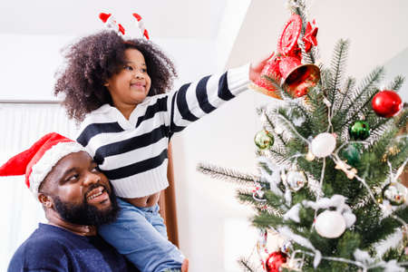 African American family help decorate the Christmas tree at home. Merry Christmas.の写真素材