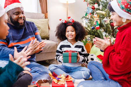 African American family surprising with a gift on Christmas day. Merry Christmas. Happy family.の写真素材