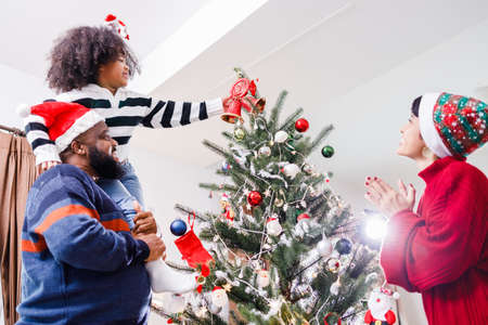 African American family help decorate the Christmas tree at home. Merry Christmas.の写真素材