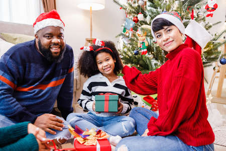 African American family surprising with a gift on Christmas day. Merry Christmas. Happy family.の写真素材