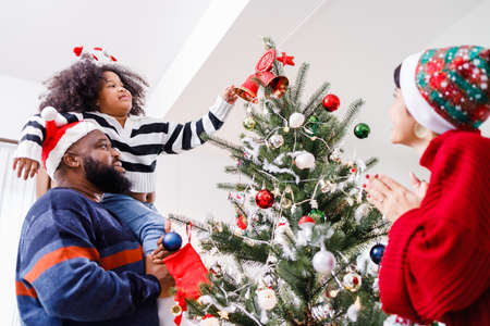 African American family help decorate the Christmas tree at home. Merry Christmas.の写真素材