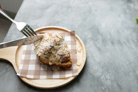 freshly baked croissants topping almond on the modern wooden plate in coffee shop. Relax timeの写真素材