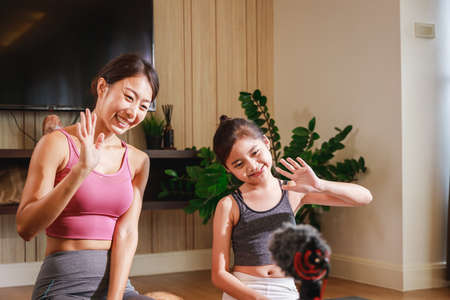 Asian woman yoga teacher and Girl filming yoga online class on video. Professional instructor in sportswear posing on VIDEO camera. Healthy lifestyle - technology at home. New normal lifestyleの写真素材