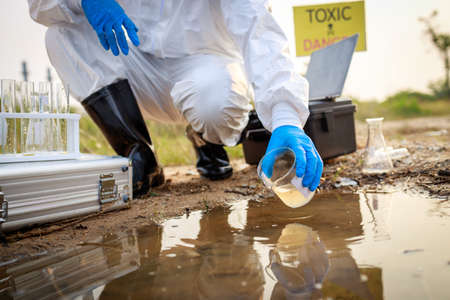 Close up the hand of Scientist in a protective suit and mask took a sample of water for analysis. Environment Issue conceptの写真素材