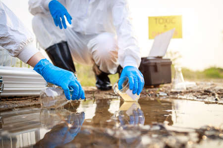 Environment Issue concept. Team of Scientists in protective suits and masks took a sample of water for analysis. Environment Issue conceptの写真素材