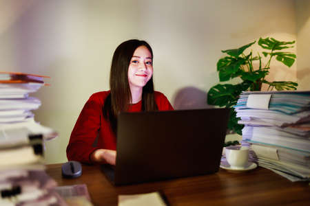 Happy woman working at home at nightの写真素材
