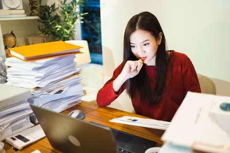 Workaholic people concept. Business Woman check reports by computer laptop during overtime at homeの写真素材