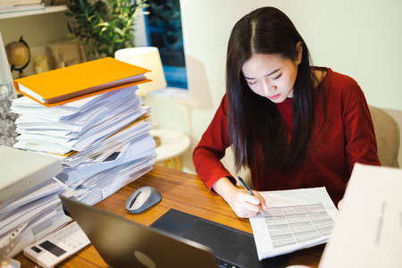 Businesswoman make the business reports by computer laptop during overtime at homeの写真素材