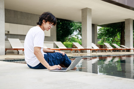 Businessman in casual wear with laptop working near swimming pool on vacation, Business remote workの写真素材