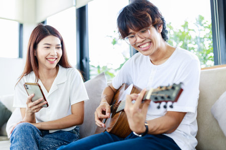 Sweet couple, Young man playing guitar and girl singing in living room, Leisure activities