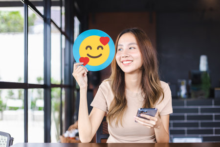 Customer experience review and feedback satisfaction service concept. Customer woman holding happy face emoji for giving good feedback ratingの写真素材