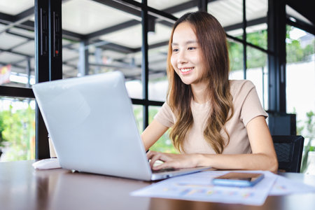 Happy young cheerful businesswoman working using her laptop in cafe. Working online technology and modern devices conceptの写真素材