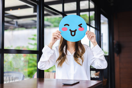 Customer experience review and feedback satisfaction service concept. Woman holding happy face emoji for giving good feedback ratingの写真素材