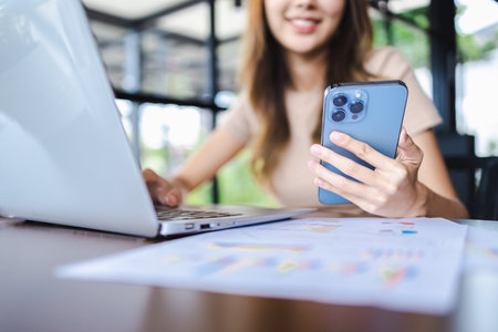 Close-up freelancer woman hands working on smartphone and laptop in a cafe. Working online technology and modern devices conceptの写真素材
