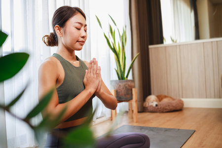 Elevate Your Home Yoga Practice with an Asian Woman in Sports Clothingの写真素材