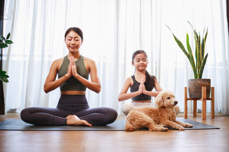Asian young mother and her daughter setting prepare to yoga and meditation pose together with dogの写真素材