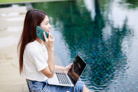 Mobile Work and Leisure, Woman on Vacation Answers Emails on Smartphone by the Poolの写真素材
