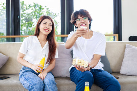 A couple sitting and watching movie together in living room, happiness and married people concept.の写真素材