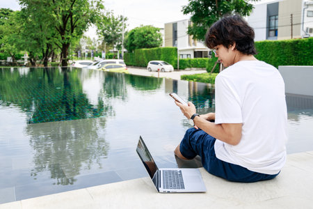 Businessman Balances Work and Leisure on Vacation by Poolside with Laptopの写真素材