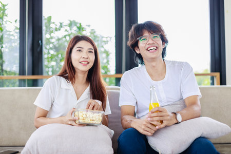 Romantic Evening, Couple Snuggling on Couch and Watching Movie Togetherの写真素材