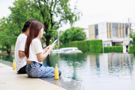 The Perfect Balance, Business and Leisure Combine for Happy Couple Working by the Pool on Vacationの写真素材