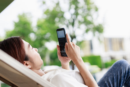 Relaxing by the Poolside, Woman on Vacation Captures Memories with Smartphoneの写真素材